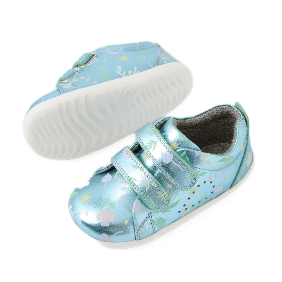 Bobux Step Up Grass Court Trainer Jelly Mint Metallic Blue toddler shoes feature a shiny blue-green finish with white soles, playful floral and animal patterns, and two velcro straps—ideal as first walker shoes. In the image, one shoe stands upright while
