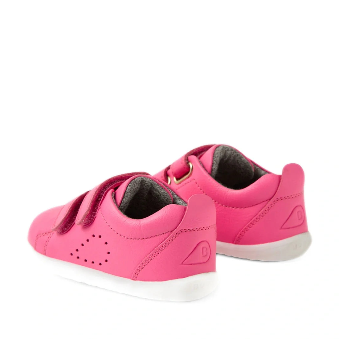 A pair of Bobux Step Up Grass Court Trainer Pink Lemonade sneakers for kids, featuring bright pink leather, Velcro straps, white soles, and designed as comfortable first walker shoes, positioned on a white background., 9420074806451, 9420074806468, 942007