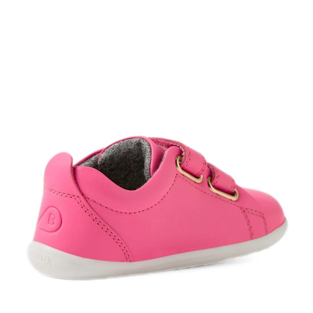 Showcased from a back-side angle on a white background, the Bobux Step Up Grass Court Trainer in Pink Lemonade is a vibrant pink leather sneaker for toddlers, featuring two velcro straps, gold eyelets, and a white sole, specially designed for wide-fit chi