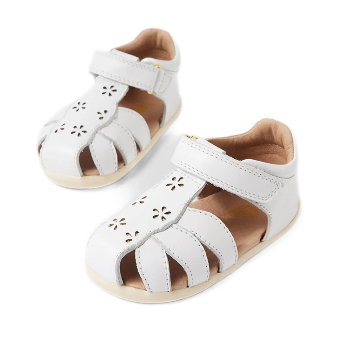 Introducing the Bobux Step Up Grass Holly First Walker Closed Toe Sandal in White—toddler sandals crafted from white leather with adorable flower cutout designs and secure Velcro straps, making them ideal as first walking sandals. Shown here against a whi