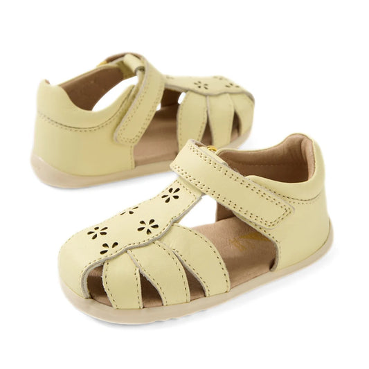 Bobux Step Up Grass Holly First Walker Closed Toe Sandal in Wax Yellow—light yellow leather toddler sandals featuring closed toes, cut-out flower designs, and Velcro straps—perfect for little ones taking their first steps.