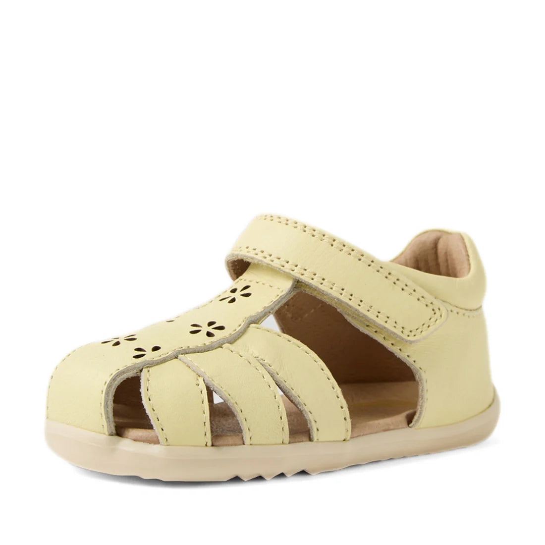 The Bobux Step Up Grass Holly First Walker Closed Toe Sandal in Wax Yellow features a pale yellow color with cut-out flower designs, closed toe, open sides, and a Velcro strap. These toddler sandals offer a soft, flexible sole and cushioned interior for a