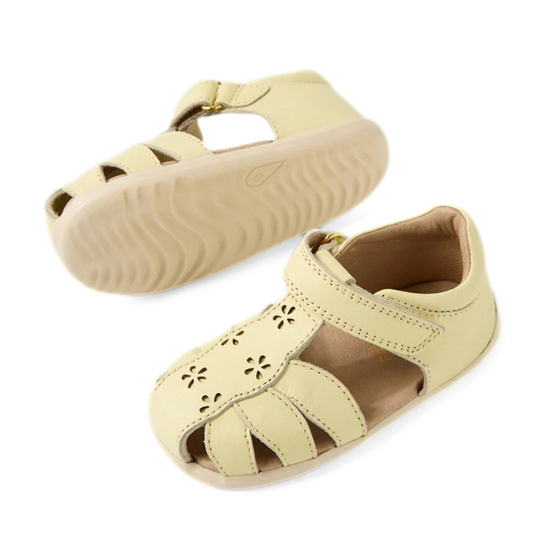 The Bobux Step Up Grass Holly First Walker Closed Toe Sandal in Wax Yellow is a pair of light yellow sandals for toddlers, featuring cutout floral designs, Velcro straps, and flexible rubber soles—perfect as first walker sandals for little ones., 94200748