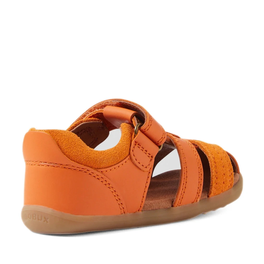 The Bobux Step Up Sandal Roam Closed Toe Sandals in Orange Peel are toddler sandals inspired by the classic Bobux Roam design, featuring a closed heel, open toe, and adjustable strap. Shown from a rear side angle, these sandals combine a light brown, slig