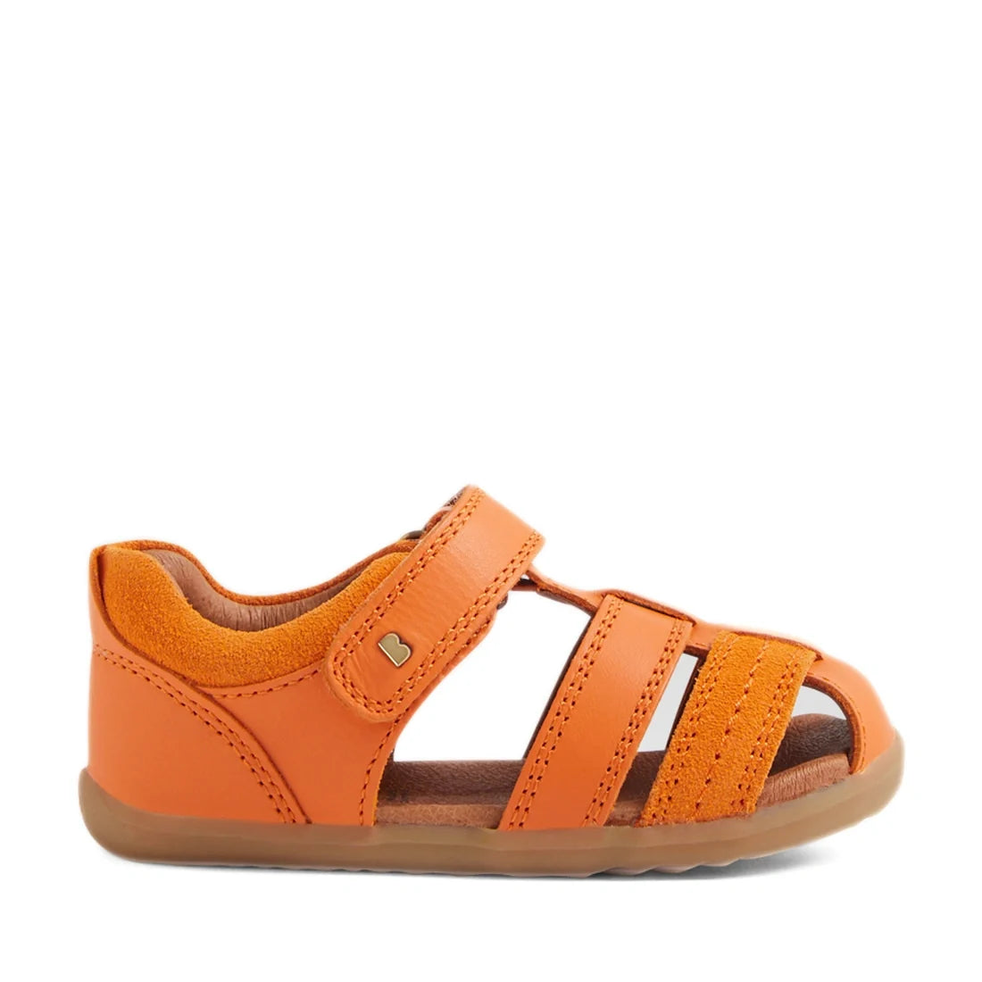 The Bobux Step Up Sandal Roam Closed Toe Sandals in Orange Peel feature bright orange leather with an open toe, closed heel, and three side straps. Designed with a Velcro closure on top and a brown flexible sole, these sandals are shown against a white ba