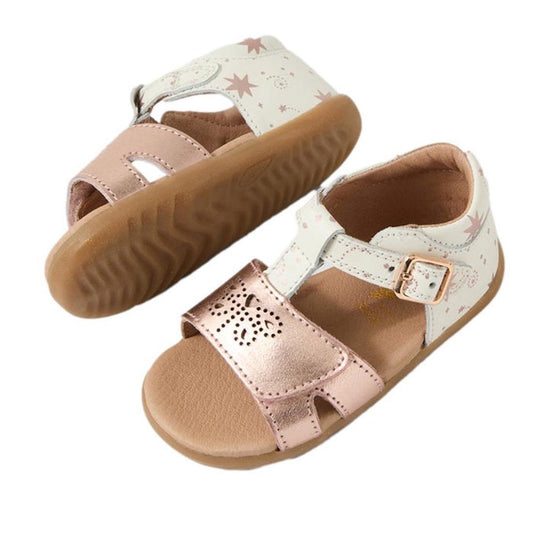 The Bobux Step Up SU Haven Star White Rose Gold Leather Sandal features tan rubber soles, white straps with pink stars, and shiny metallic rose gold front straps with cutout and adjustable buckle for the perfect toddler fit.