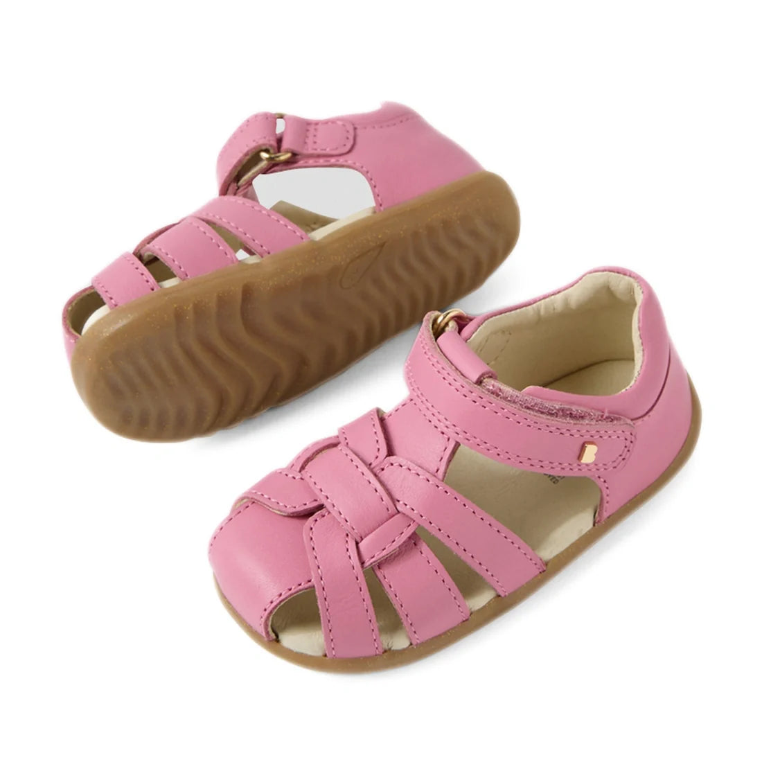 The Bobux Step Up Sandal Skip Twist Closed Toe Sandals in Cashmere Rose Pink feature woven leather straps, an adjustable Velcro closure, open toes, and light brown rubber soles—making them the perfect stylish first walking leather sandals for toddlers., 9