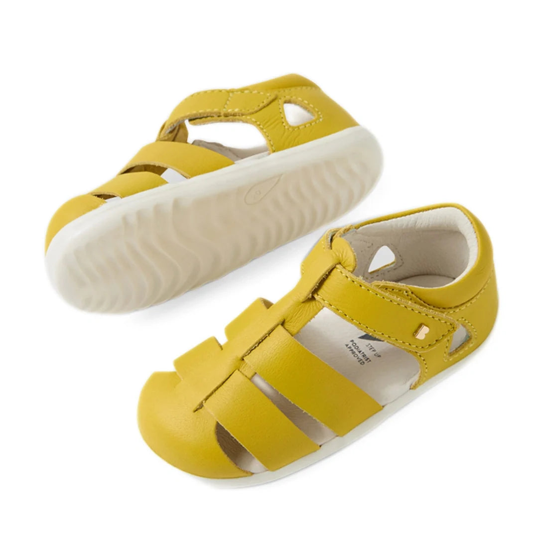 A pair of Bobux Step Up SU Toddlers Tidal Mango Mint Yellow Closed Toe Sandals featuring white soles, open toes, and a closed heel. Made from water-friendly leather, one sandal stands upright while the other rests on its side to showcase the textured sole