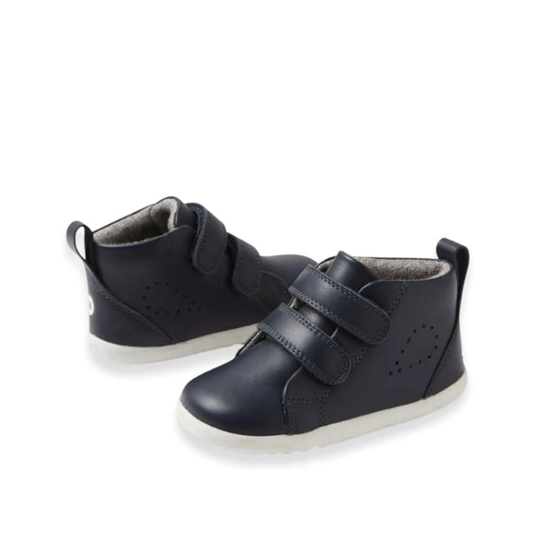 The Bobux Step Up Grass Court Hi Boot Navy toddler sneakers feature a navy blue design with white soles, two velcro straps, and a small pull tab at the back. This Hi Top Boot is displayed against a plain white background., 9420075771741, 9420075774490, 94