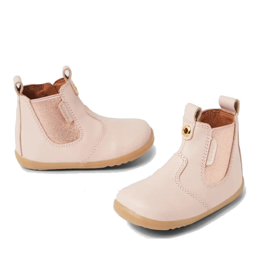 The Bobux Step Up Jodhpur Boot in Cameo Rose Pink is a light pink unisex leather toddler boot with elastic side panels, tan rubber soles, and front/back pull tabs—perfect stylish first walkers.