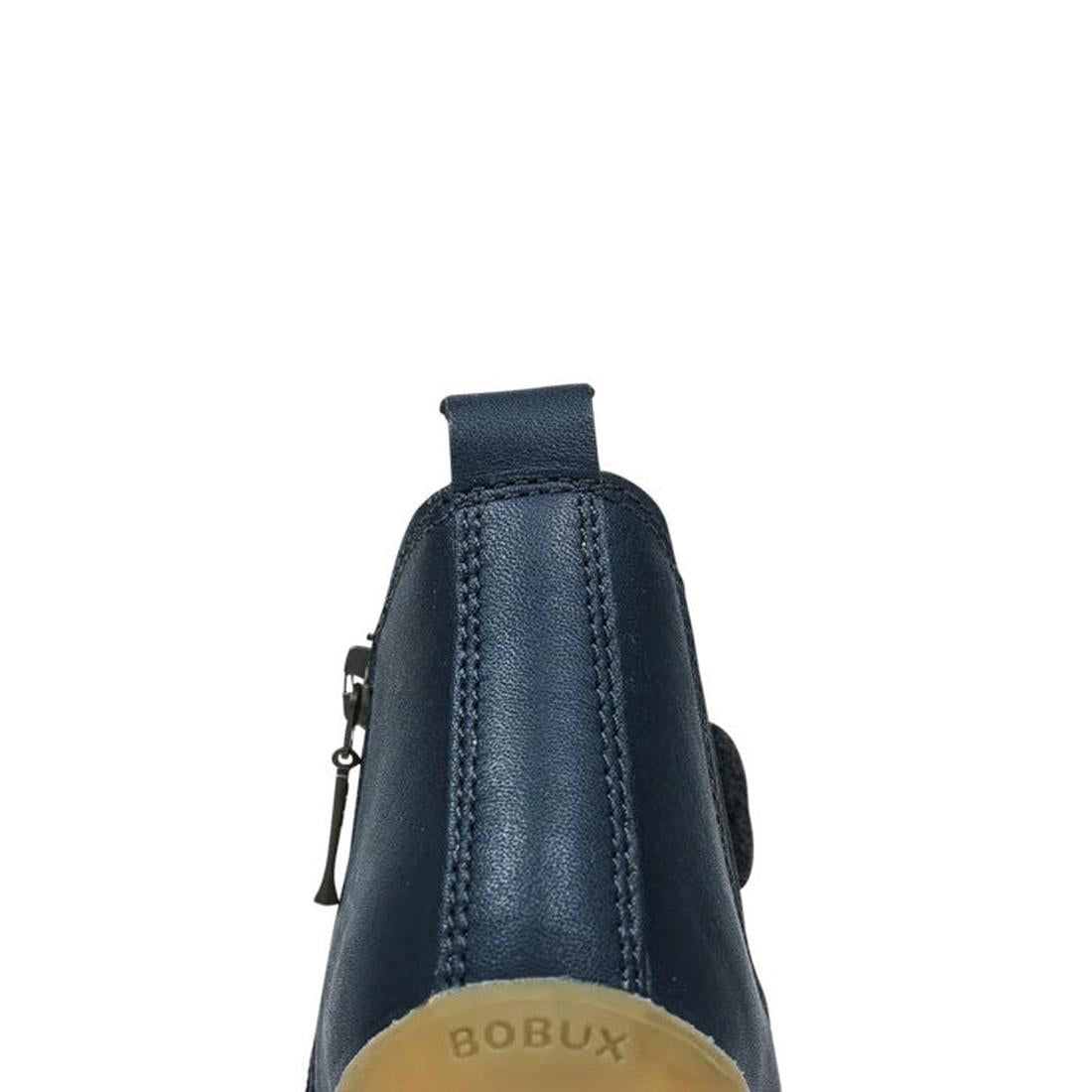 A close-up rear view of the Bobux Step Up Jodphur Boot Navy 721929A shows its navy leather, pull tab, visible stitching, and BOBUX embossed on the tan sole—perfect for stylish first walkers., 9420062048535, 9420062048542, 9420062048559, 9420062048566