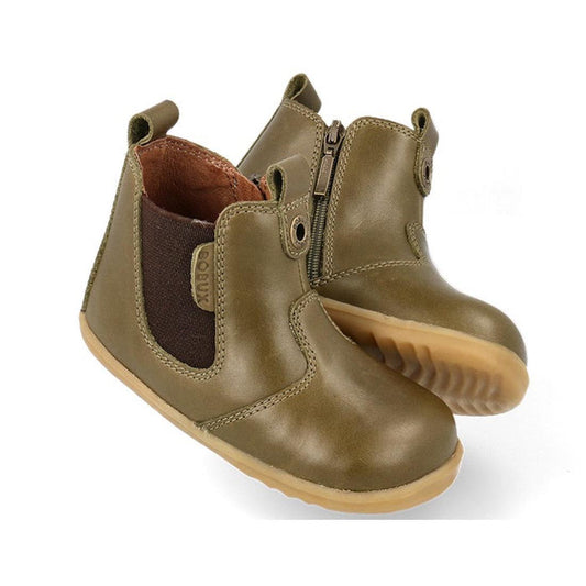 The Bobux Step Up Jodphur Boot Olive 721960 is an olive green unisex toddler ankle boot with leather upper, side zipper, brown elastic panels, pull tabs, and tan rubber soles—ideal first walkers shown on a white background.