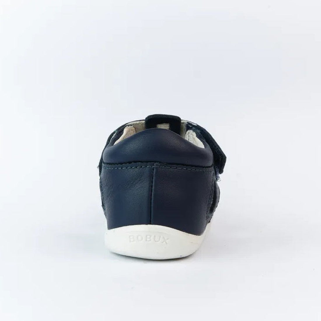 The Bobux Step Up US Tidal Navy Closed Toe Sandal 732503 is a navy blue first walker shoe shown from the back, with smooth leather, a white sole embossed with BOBUX, a small heel loop, and a plain white background., 9420068502574, 9420068502581, 942006850