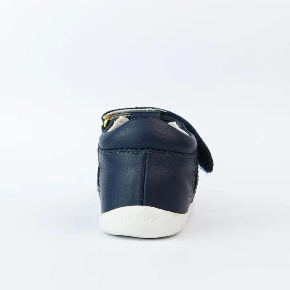 The Bobux Step Up Tropicana II Navy Sandal 732301 Quick Dry features a navy design with a white sole, closed heel, and partially open Velcro strap for style and comfort. "BOBUX" is embossed on the sole. Shown from the back against a plain background., 942