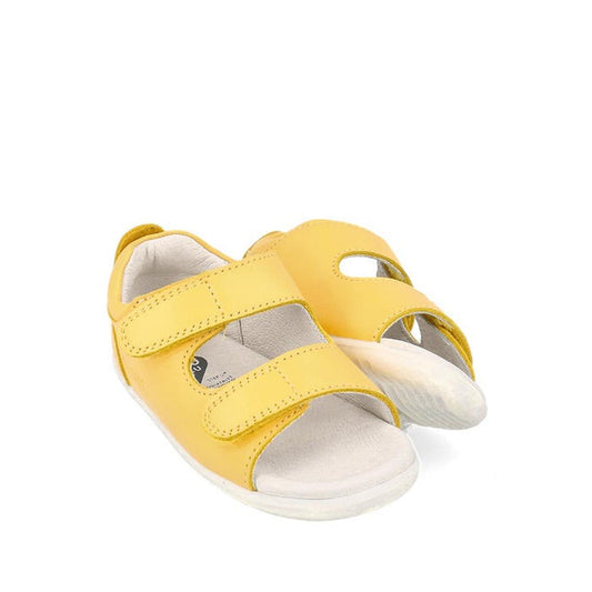 The Bobux Step Up - Topia First Walker Sandal 751304 in Pineapple Yellow features double Velcro straps and open toes. Displayed on a white background, one stands upright while the other tilts to reveal the sole—ideal for toddlers' first steps.