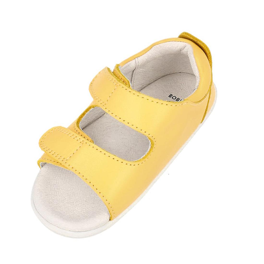 The Bobux Step Up - Topia First Walker Sandal 751304 in Pineapple Yellow features two adjustable Velcro straps and a white cushioned sole, making it perfect as a first walking sandal for children. Shown on a white background., 9420075763722, 9420075763654