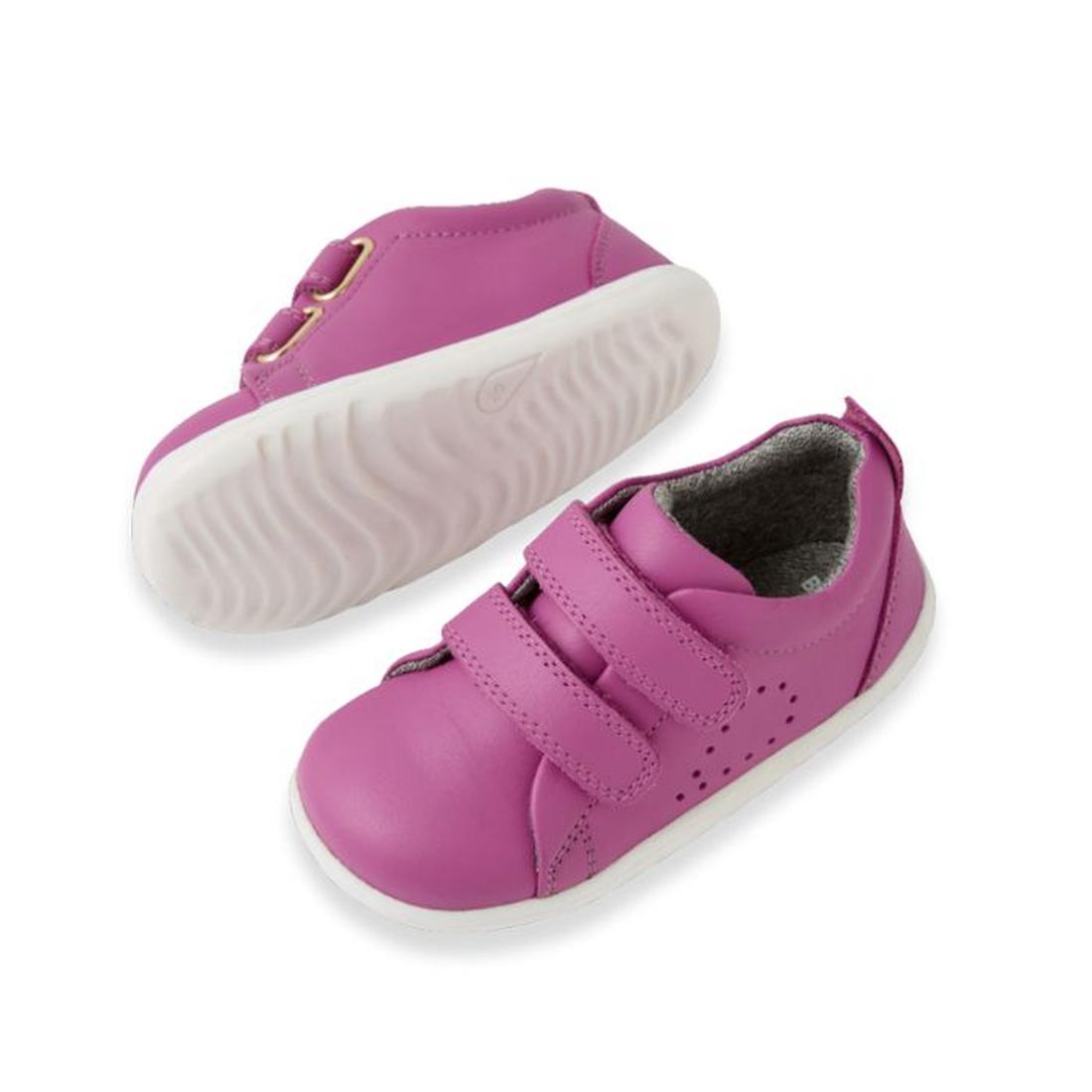 A pair of small, bright orchid purple Bobux Step Up Grass Court Trainer leather shoes with white soles and two velcro straps, shown on a white background. Perfect as stylish first walker shoes for your little one., 9420074806499, 9420074806505, 9420074806