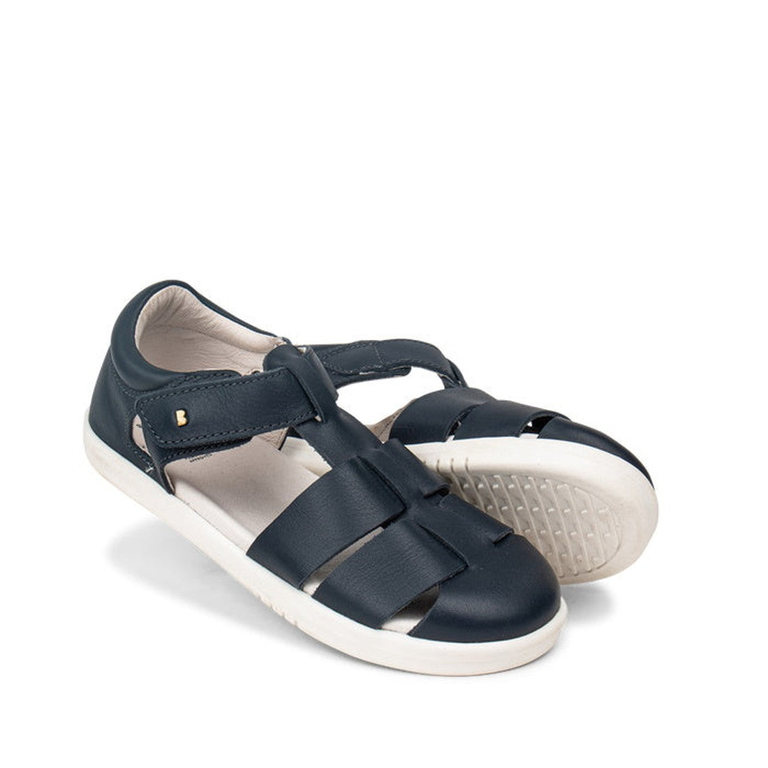 The Bobux Kid+ Tidal Closed Toe Quick Dry Sandal Navy (834404A) features navy blue leather, white rubber soles, and adjustable velcro straps. One sandal is positioned slightly ahead of the other in the image.