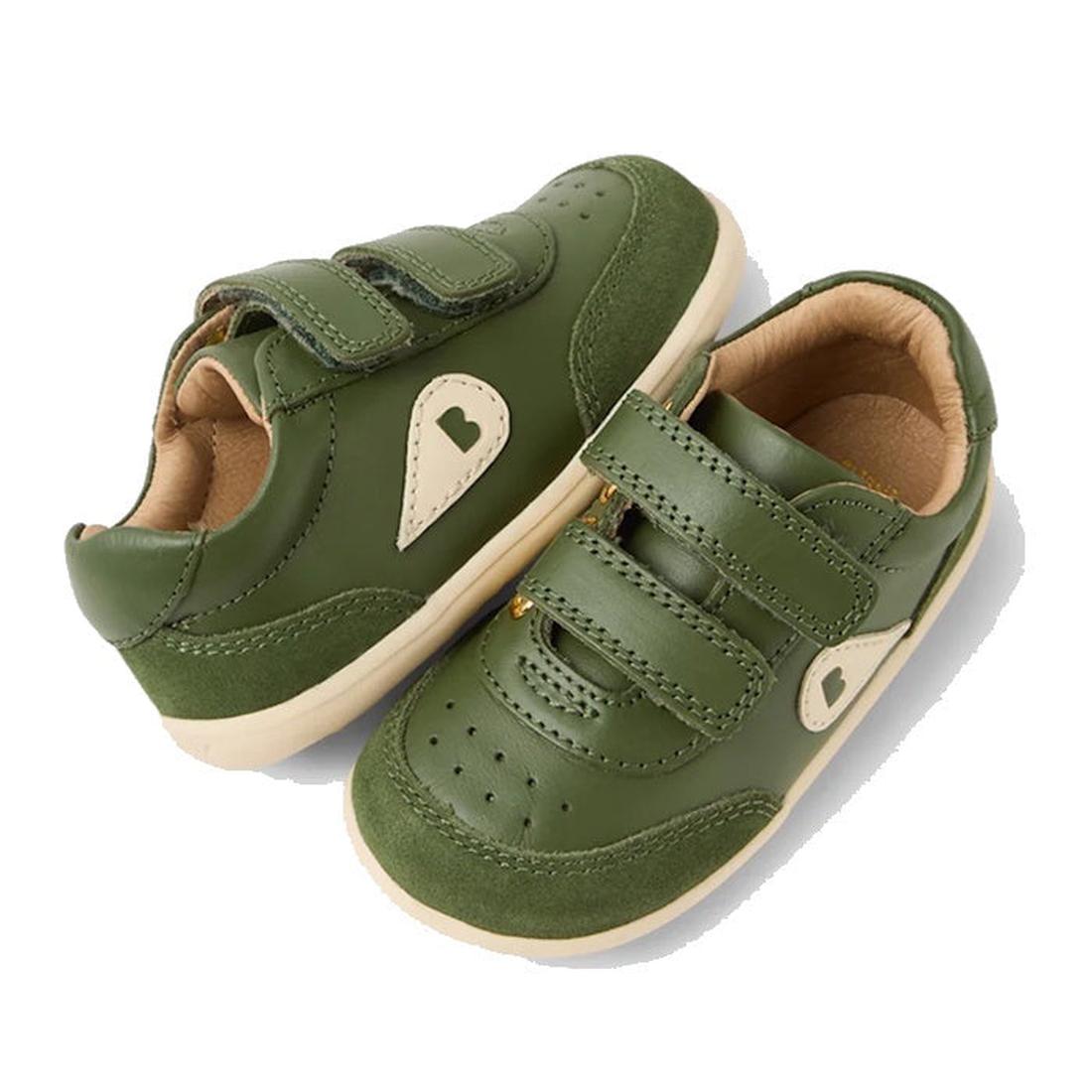 The Bobux Step Up SU Champ II Sneaker in Bronze Green features tan soles, cream heart-shaped side accents, and adjustable hook-and-loop straps for easy fastening—perfect first walker shoes.