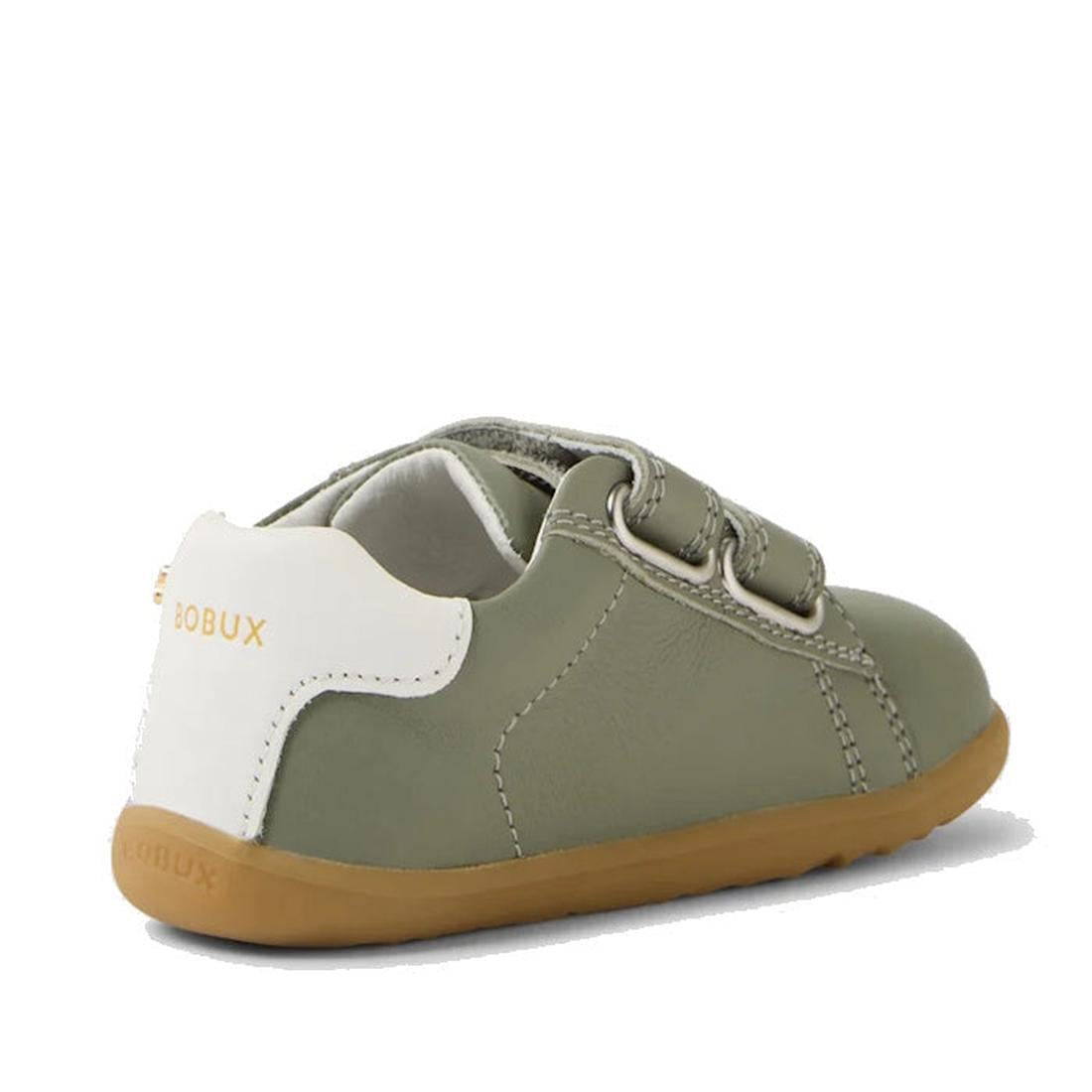 The Bobux SU Step Up Maverick Leather Toddlers Sneaker in Vetiver Green is a small olive-green first walker with a white heel, light brown sole, and adjustable Velcro strap. "BOBUX" is printed in gold on the back white heel tab., 9420074836649, 9420074836