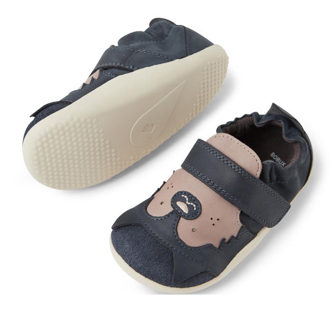 Two Bobux XP Xplorer Howl First Walking Shoes in navy feature soft beige soles, a bear face on the toe, and an adjustable Velcro strap. One pre walker shoe faces up; the other displays its sole., 9420074806000, 9420074806017, 9420074806024, 9420074806031,