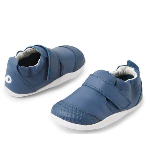 The Bobux XP Xplorer First Walking Shoes Go Vintage Indigo Blue are pre-walker leather shoes with white soles and Velcro straps, featuring a flexible sole for comfort—ideal for your toddler's first steps.