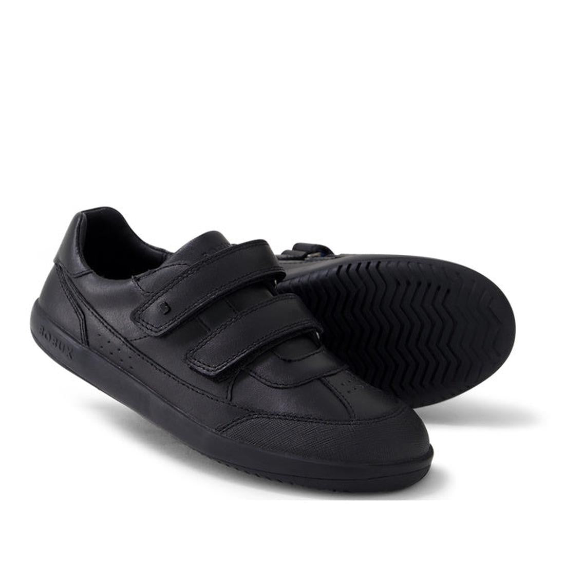 The Bobux Kid+ Black School Leather Shoe Traverse Trainer features two adjustable straps—one upright, one sideways—and a durable tread pattern, making it the perfect sneaker-style school shoe for kids.