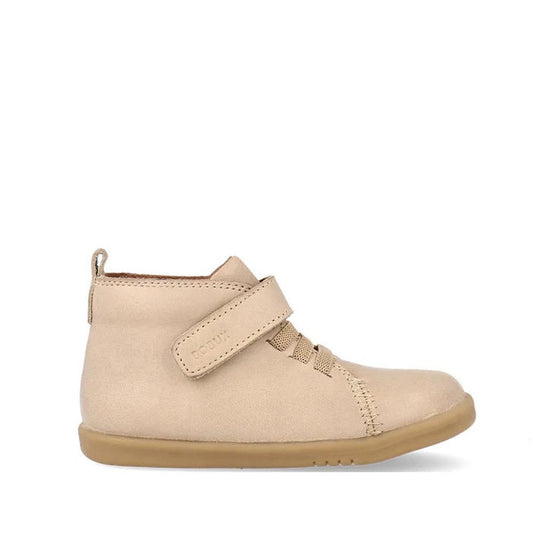The Bobux Iwalk Voyager Toddlers Leather Boot in Oat Milk Beige (650604) is a unisex ankle boot featuring a flexible sole, visible stitching, elastic laces, and a hook-and-loop strap, pictured left-side profile on a white background.