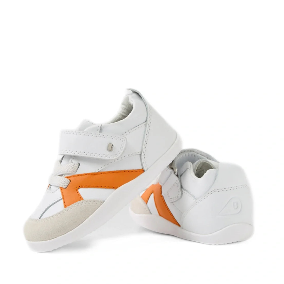 Two Bobux Xplorer XP Chase White Orange Peel First Walker Crawler shoes are shown—white toddler sneakers featuring orange accents, velcro straps, and beige toe patches. Designed for pre-walkers with a flexible sole, they provide comfort and support for li