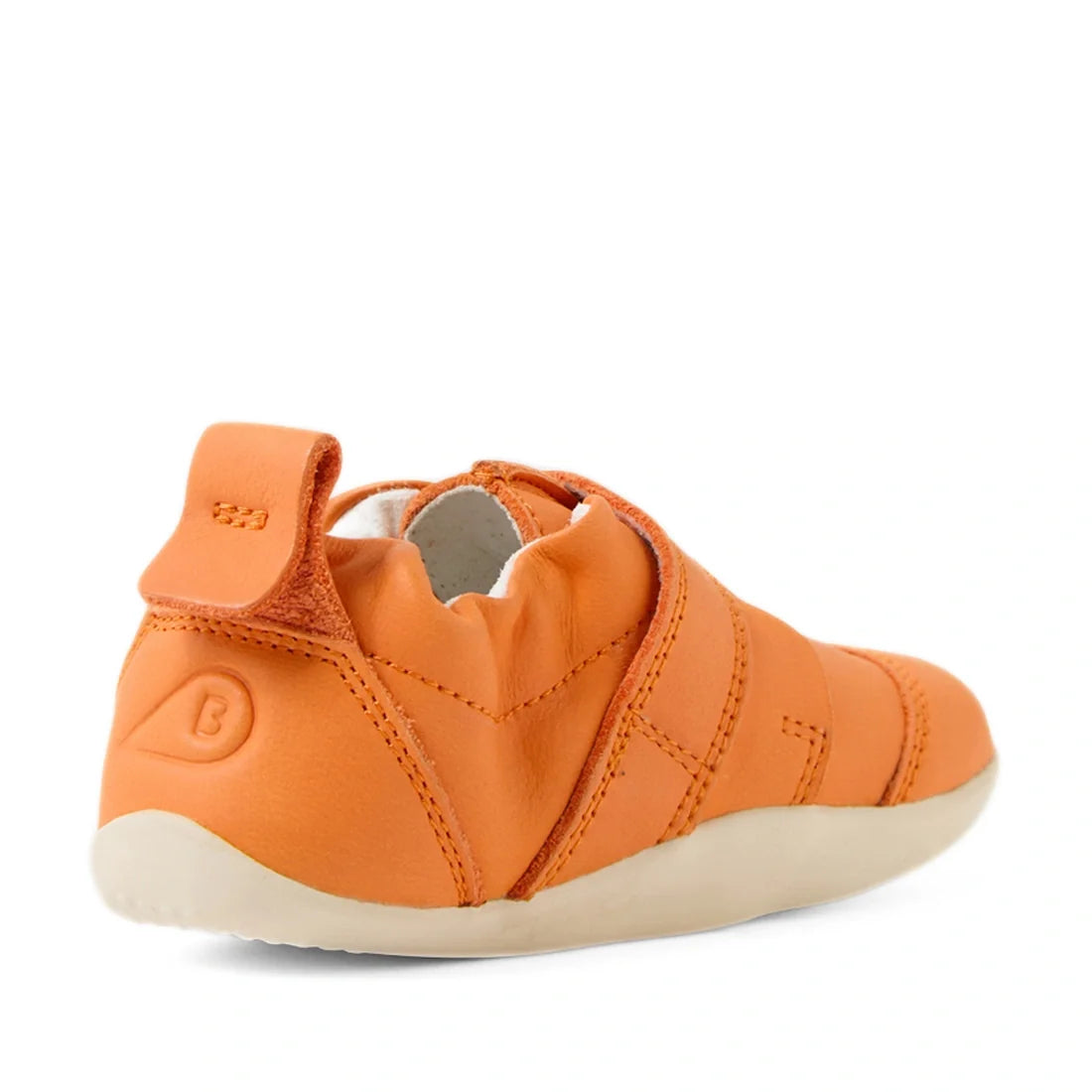 The Bobux XP Explorer Little Sprouts Carrot Top First Walker Orange baby shoe is displayed from the back, highlighting its soft, flexible cream-colored sole. Designed as a flexible sole baby shoe, it features a Velcro strap and elastic around the ankle fo