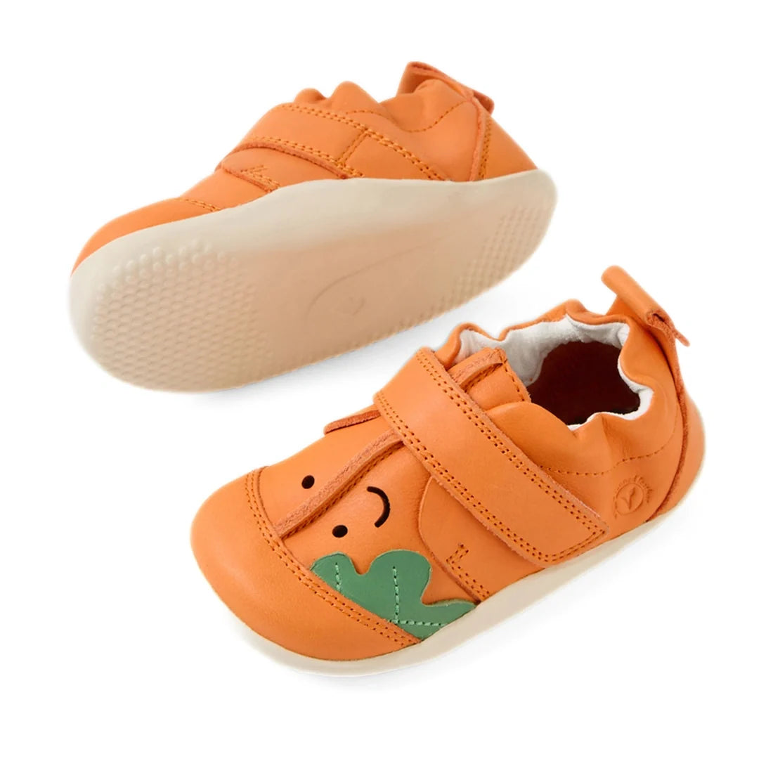 The Bobux XP Explorer Little Sprouts Carrot Top First Walker Orange features two vibrant orange toddler shoes with white soles, Velcro straps, and a playful face design accented by green leaf details on the front—making these flexible sole baby shoes perf