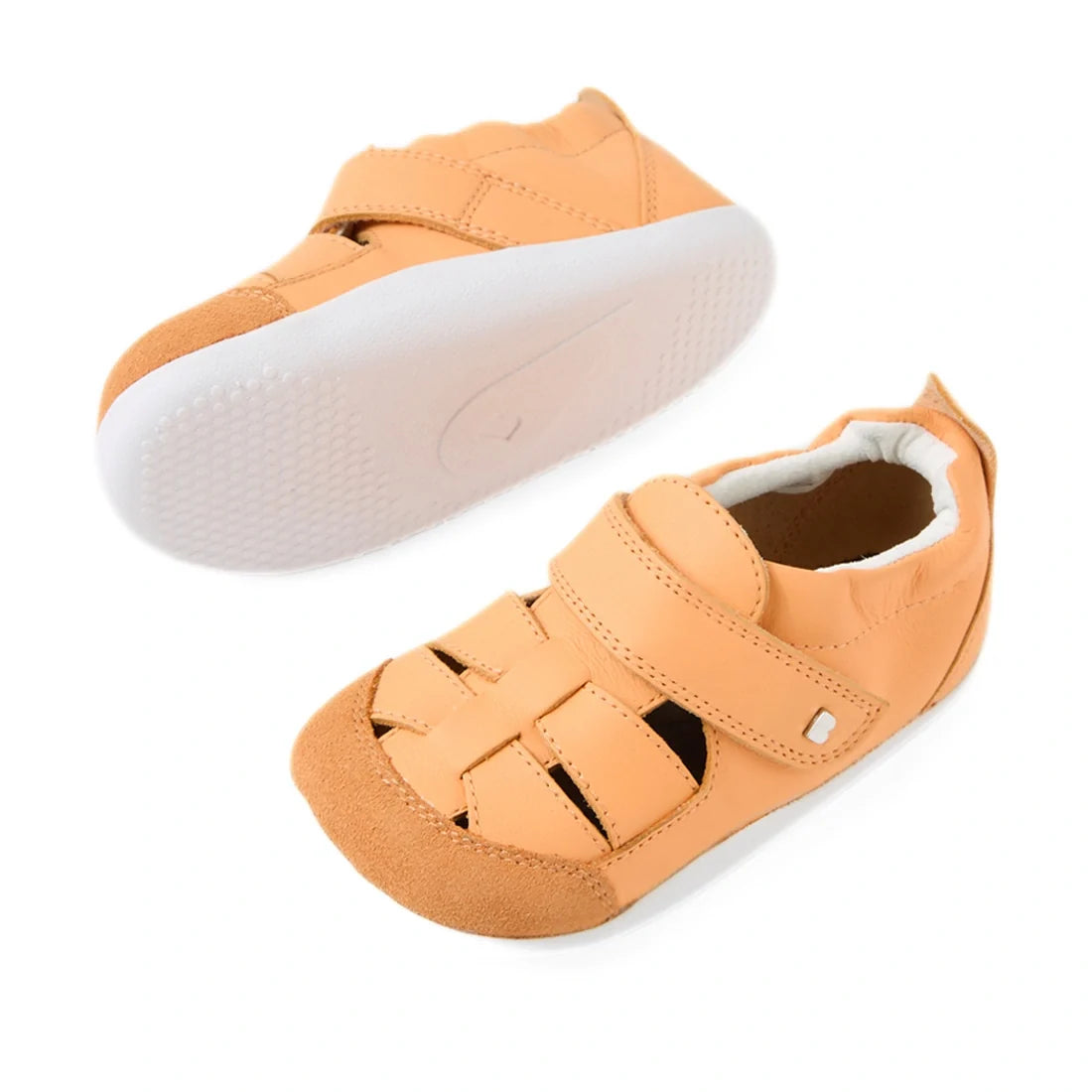 A pair of Bobux XP Explorer Maris First Walker Sandal Peach Jelly toddler sandals with Velcro straps, closed toes, flexible white rubber soles, and tan leather uppers. One sandal stands upright while the other is tilted to display its flexible sole, makin