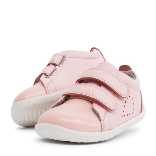 The Bobux Step Up SU Grass Court Trainer 728909J in Seashell Pink is a toddler leather sneaker with white soles, two Velcro straps, and side perforations—ideal for first walkers.
