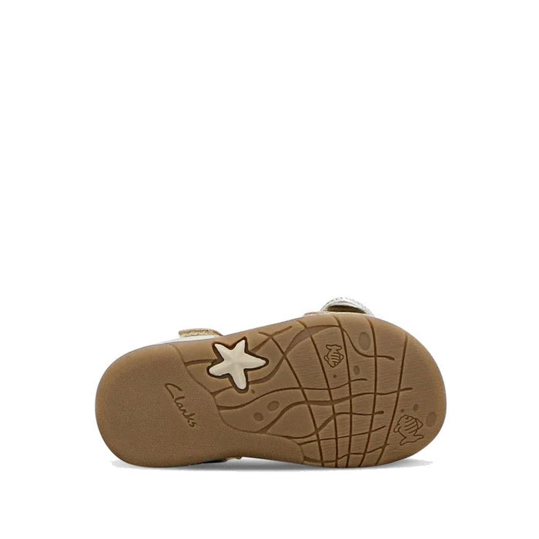 Bottom view of the Clarks Samara Toddlers Gold Leather Sandal (D Narrow Width) shows a textured rubber sole with embossed stars and seashells. "Clarks" is printed near the heel. Perfect for toddlers needing stylish, narrow-fit sandals. White background., 