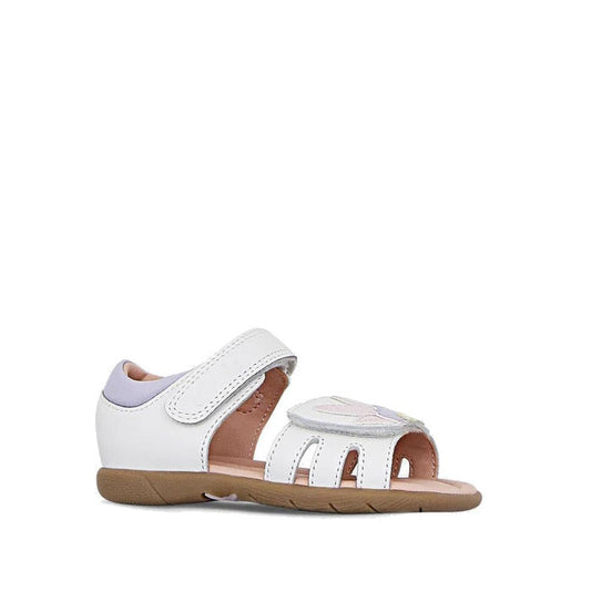 The Clarks Saskia White Toddlers Leather Sandal (E Average Width) features a closed heel, adjustable velcro ankle strap, open toe, tan rubber sole, light purple accents, and a decorative front strap detail for stylish comfort.