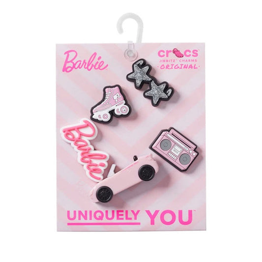 The Crocs Jibbitz 5 Pack - Barbie New Style includes roller skate, Barbie logo, pink boombox, and two glittery star charms on a pink-striped card marked “UNIQUELY YOU” to decorate your shoes.