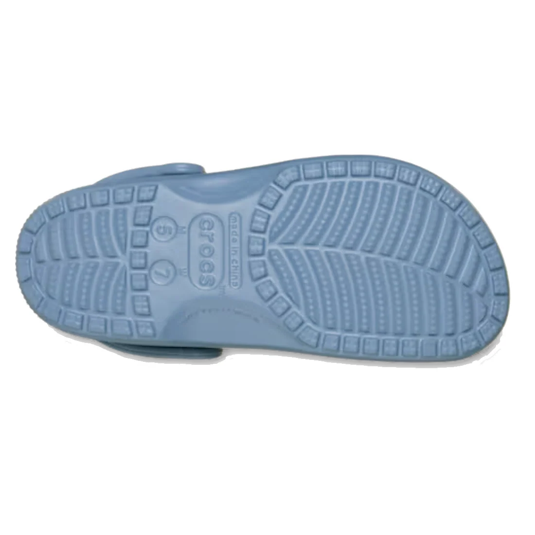 The image displays the bottom view of the Crocs Classic Clog Astro Blue Adults Unisex, highlighting its textured rubber sole with tread patterns designed for grip.