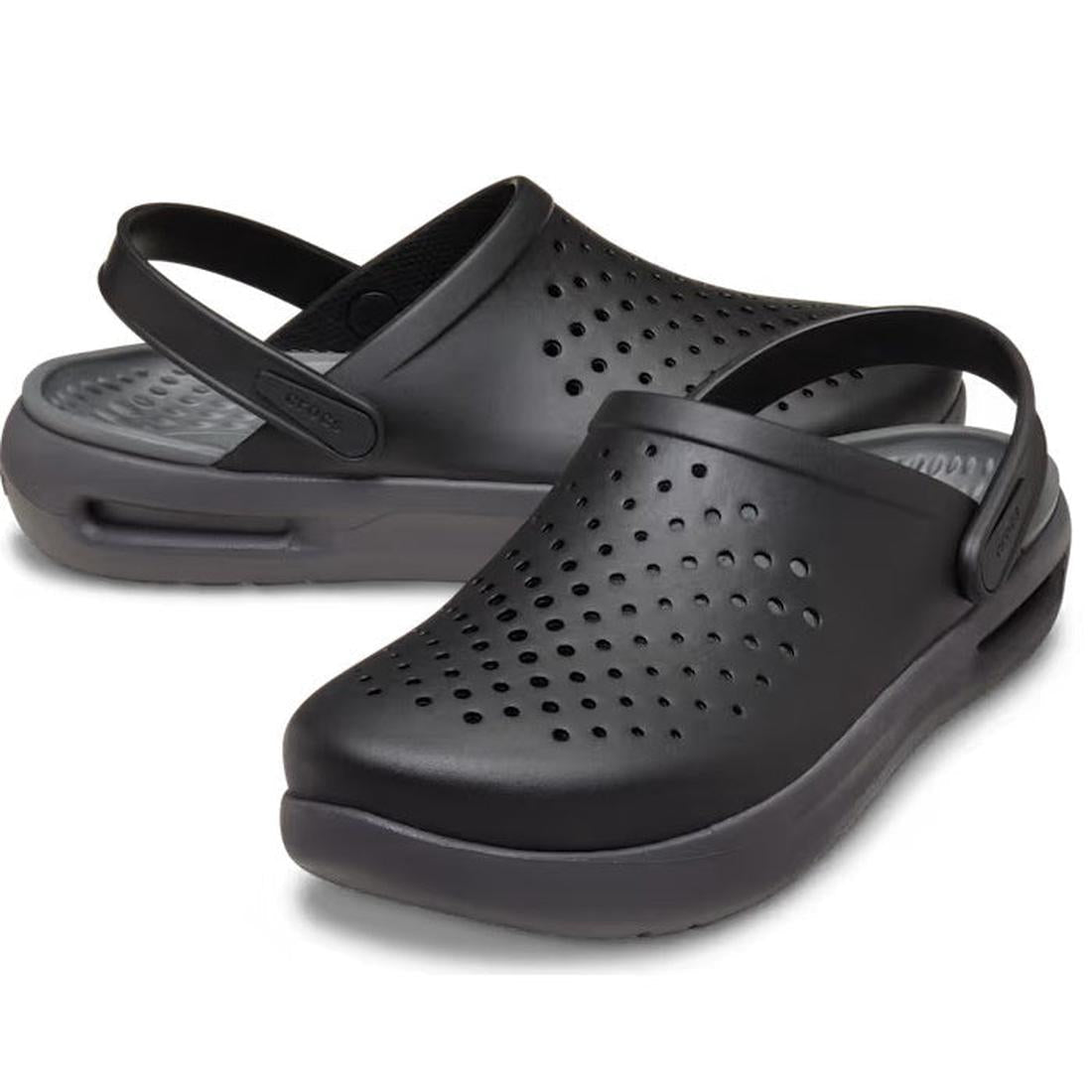 A pair of Crocs In Motion Clog Womens & Mens Full Black with perforated uppers, closed toes, adjustable back straps, and thick cushioned soles for comfort are shown on a white background.