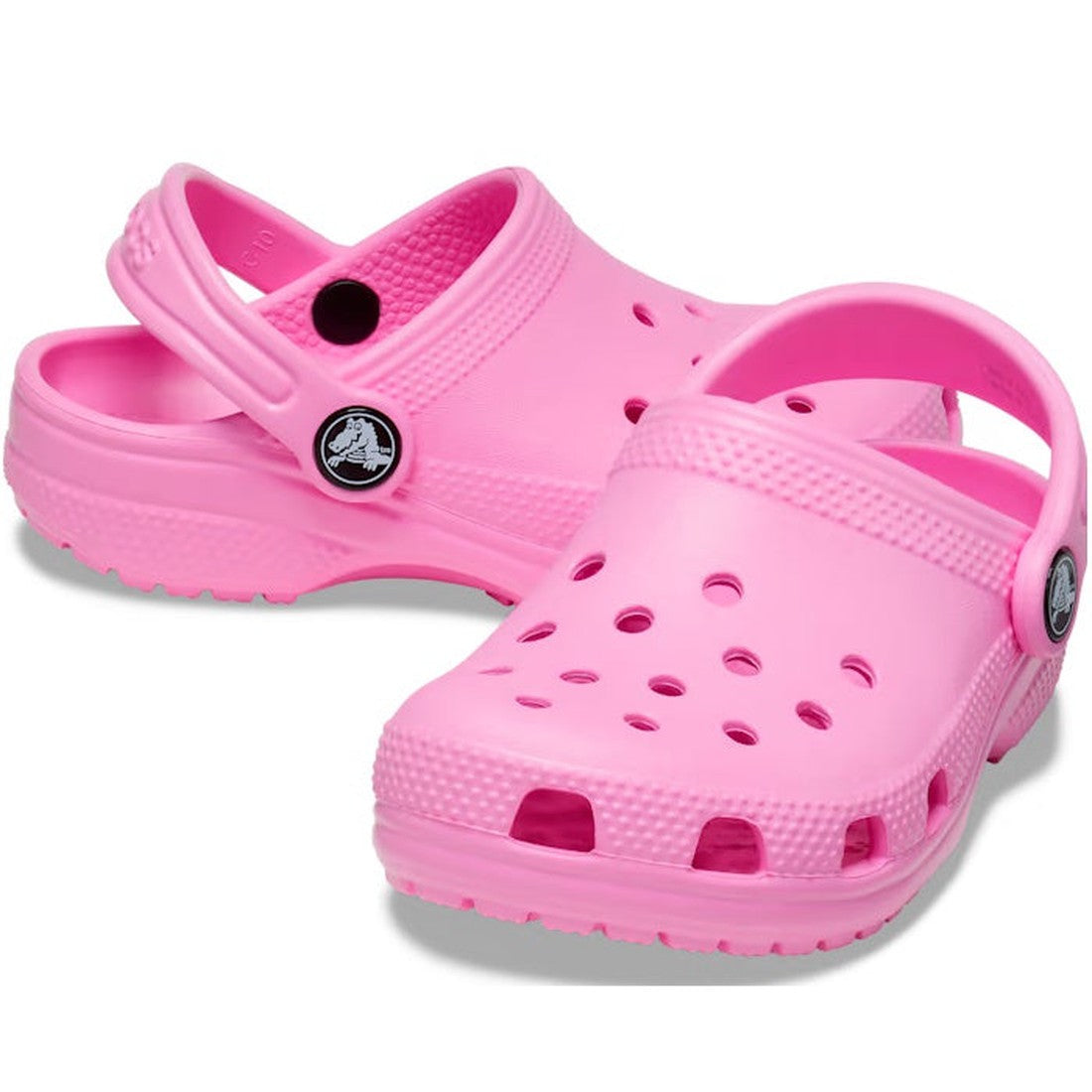 The Crocs Kids Youths - Classic Clog K in Taffy Pink features ventilation holes, adjustable heel straps, and textured soles. Shown on a white background, these water-friendly sandals are ideal for everyday wear.