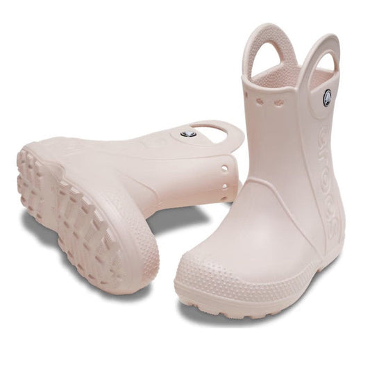 A pair of Crocs Kids - Handle It Rain Boot Quartz Pink - Gumboots with pull handles and textured soles, one standing upright and the other lying on its side, both waterproof in light pink.