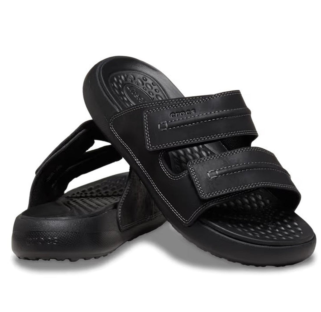 A pair of Crocs - Mens Yukon Vista II LR Sandals Slide Black with two adjustable velcro straps and textured footbeds; one sandal stands upright while the other is angled in front.