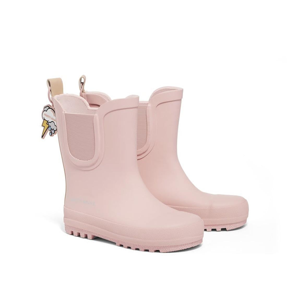 The Pretty Brave Puddle Boot Ankle Rainboot NEW in Muted Blush Pink features chunky soles, elastic side panels, and a waterproof design. One kids boot includes a decorative cloud and lightning bolt keychain on the back.