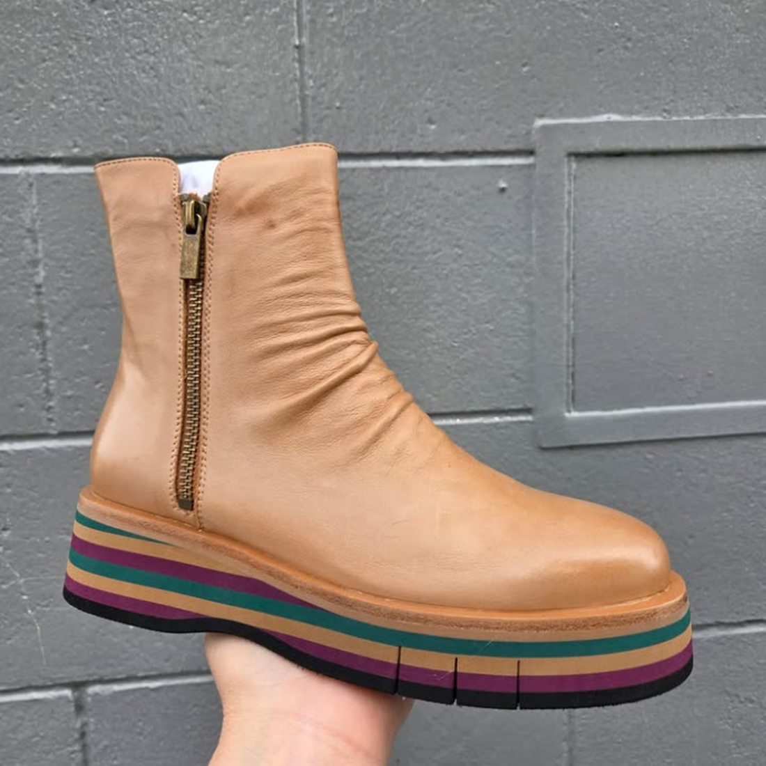 The Django & Juliette Ganni Cognac Tan Green Leather Heeled Boot features a gold zipper and thick platform sole with black, green, purple, and brown layered stripes, shown against a gray textured wall., 51110, 4434754550355, 4434754550362, 4434754550379, 