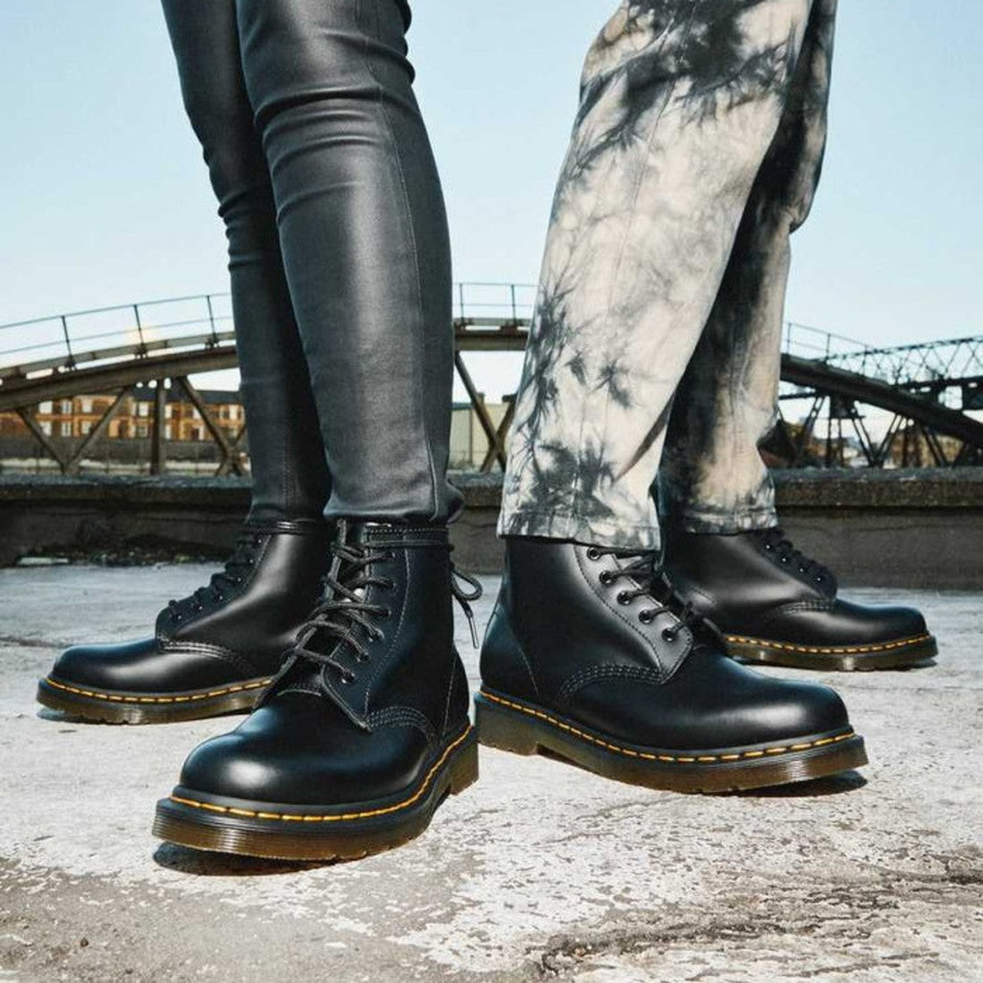 Two smiling friends in Dr Martens 101 6 Eye boots, classic black with yellow stitching, sturdy soles, and easy lace-up closures.  ksnz, 190665350715, 190665350722, 190665350739, 190665350746, 190665350753, 190665350760, 190665350777, 190665350784, 190665350791, 190665350807, 190665350814
