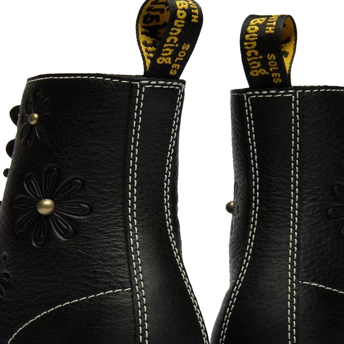 Close-up of the back of two Dr Martens Women's 1460 Pascal Flower Black Grizzly Leather Boots with white stitching, floral embossing, and yellow pull tabs reading "WITH BOUNCING SOLES" in black and yellow text., 52216, 190665781137, 190665781144, 19066578