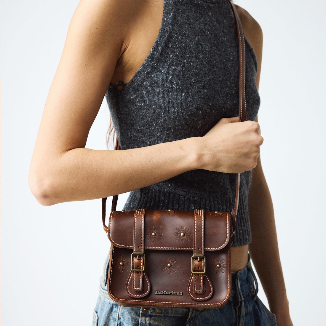 A parent holds the Dr Martens Leather Cross Body Satchel, Amber Tan, with sturdy sole and easy buckle closure—a family favorite.  ksnz, 190665799613