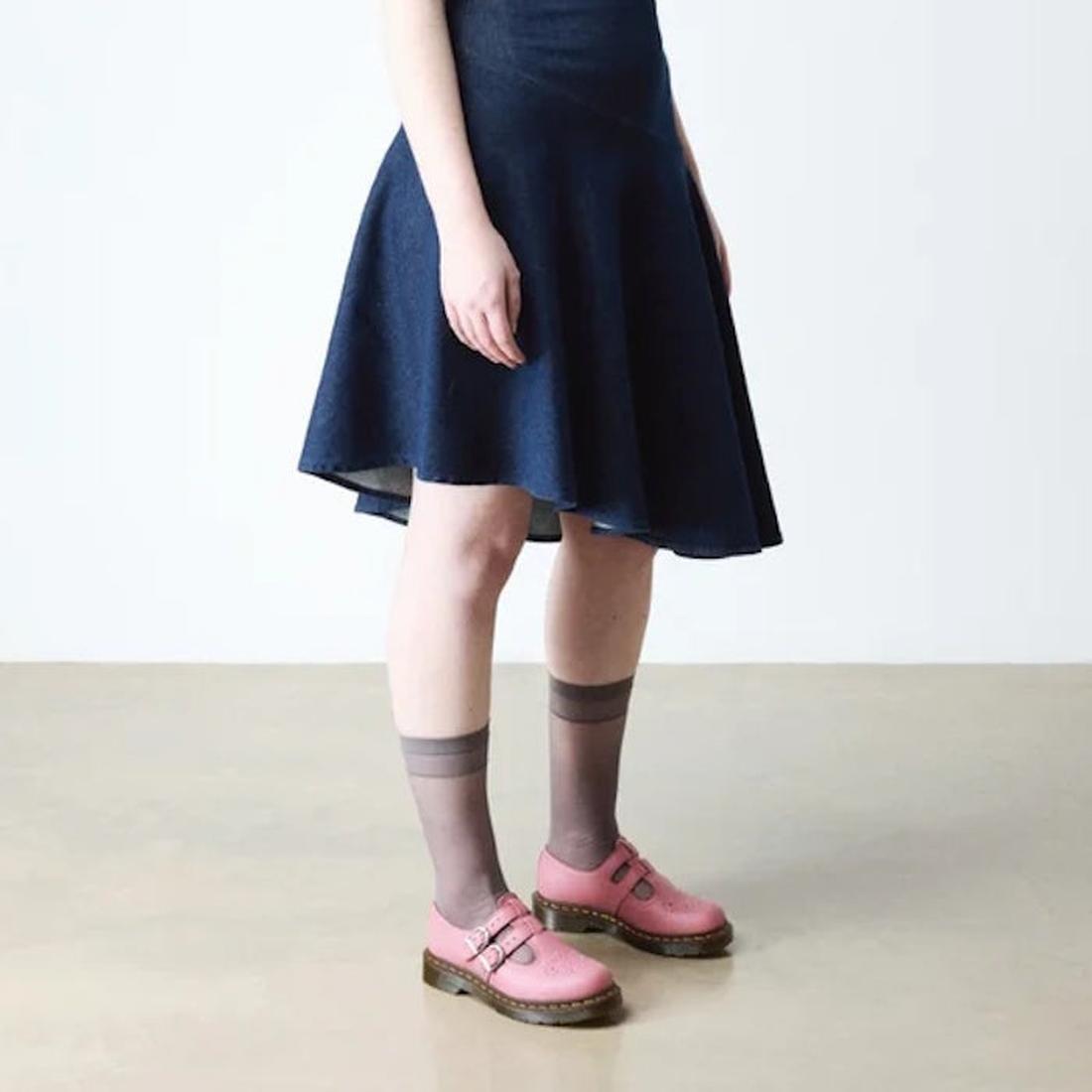 A person wearing a dark blue dress, sheer gray ankle socks, and Dr. Martens 8065 2 Strap Mary Jane Shoe in Dusky Rose Pink stands on a beige floor against a plain white background., 50241, 50242, 50243, 50244, 50245, 50246, 50247, 50241, 190665781861, 190