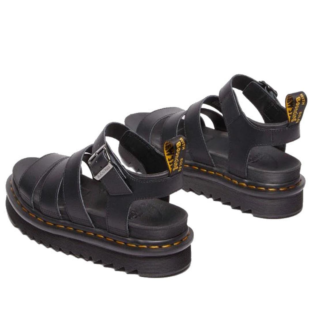 A pair of Dr Martens Blaire Sandals on a white background, showing from the heels to the front. Seeing the outer foot side of the left foot and the inner side view of the right foot and bakc strap with dr martens iconic pull tab and yellow stitching aroun