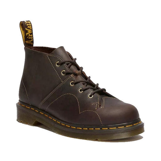 A dark brown Dr. Martens Crazy Horse Church Monkey leather boot with a 5 eye lace-up closure, yellow stitching, and a pull tab on the heel.