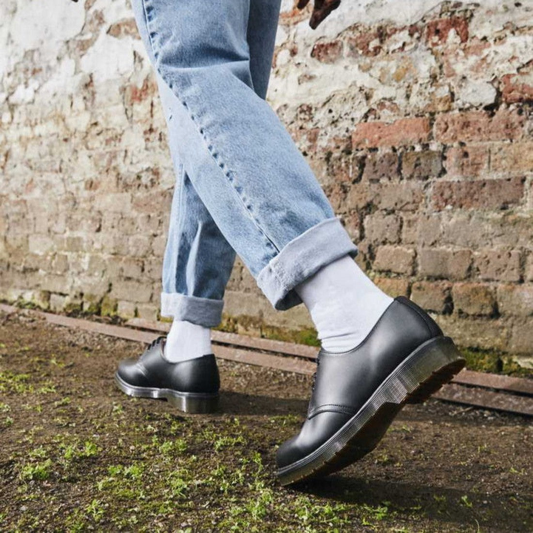 A child sports Dr Martens Doc Double Doc Sock Unisex White with sturdy black lace-up shoes, perfect for outdoor play and blister-free fun.  ksnz, 190665563085, 190665563078